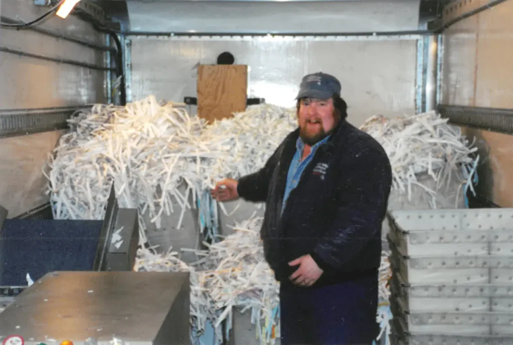 Historical photo of Country Mile Document Destruction owner standing among piles of shredded paper inside his traveling shredder truck - 2