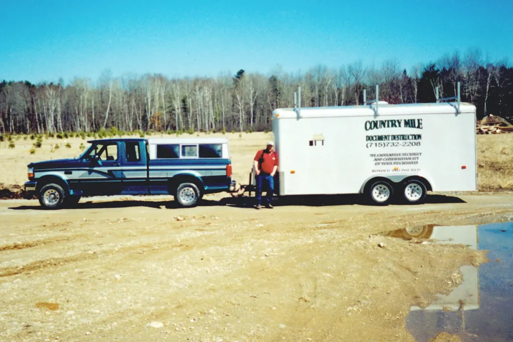 Historical photo of Country Mile Document Destruction owner sitting in front of a truck towing his mobile paper shredder trailer